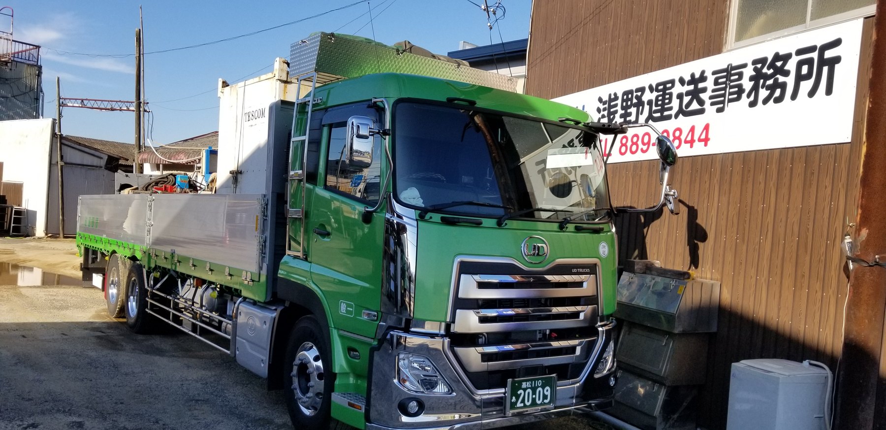 浅野運送事務所の看板と、敷地内の13t大型平ボディ車